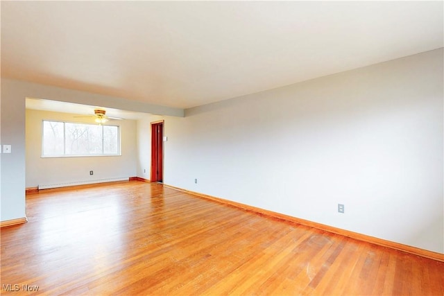empty room featuring a ceiling fan, baseboards, light wood-style floors, and baseboard heating