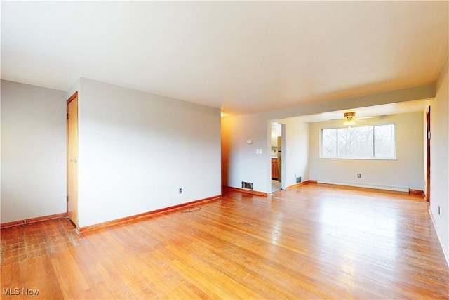 unfurnished room featuring baseboards, visible vents, light wood-type flooring, and a baseboard radiator