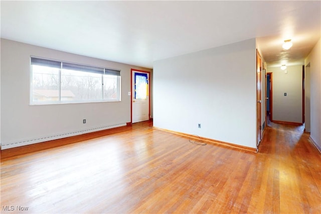 unfurnished room with baseboards, light wood-style floors, and a baseboard heating unit
