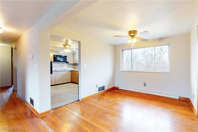 spare room featuring a baseboard radiator, visible vents, light wood-style flooring, and ceiling fan
