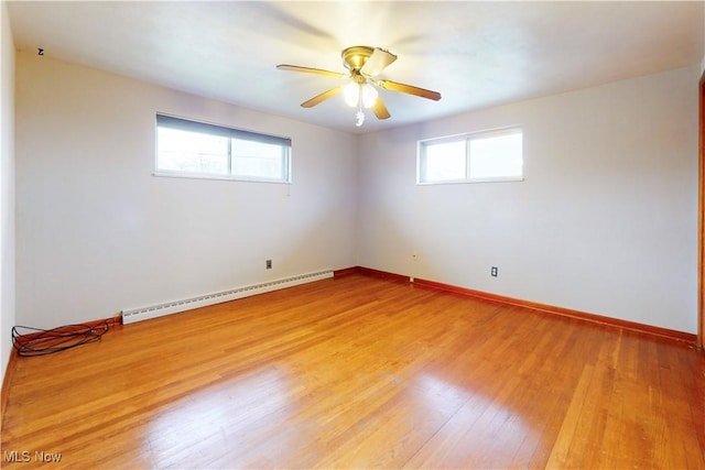 spare room featuring light wood finished floors, a baseboard radiator, ceiling fan, and baseboards