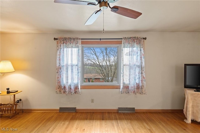 interior space featuring wood finished floors, visible vents, a ceiling fan, and baseboards