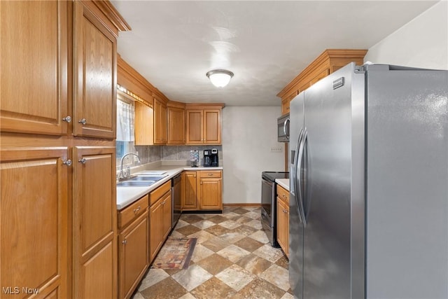 kitchen with decorative backsplash, stainless steel appliances, light countertops, a sink, and baseboards
