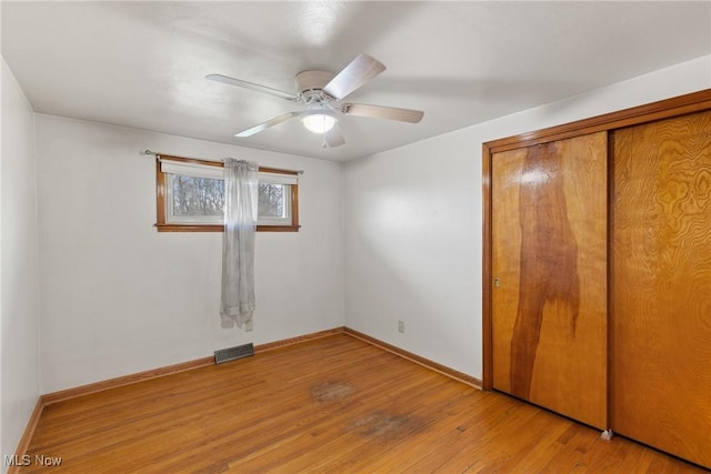 unfurnished bedroom with light wood-style floors, a closet, ceiling fan, baseboards, and visible vents