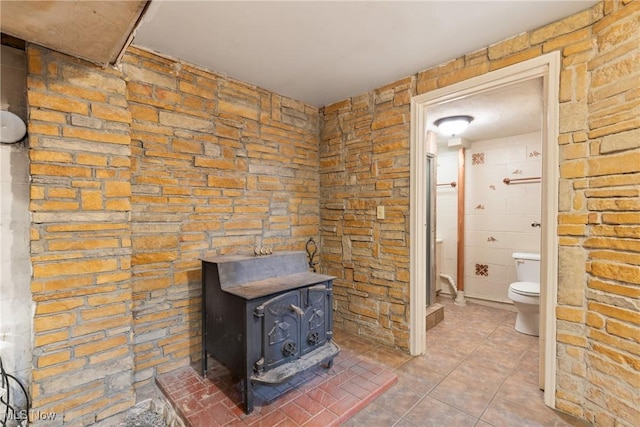 full bathroom with toilet, a wood stove, a shower stall, and tile patterned floors