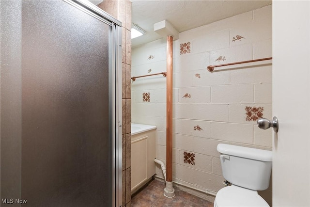 full bath with tile patterned floors, toilet, a shower stall, and concrete block wall
