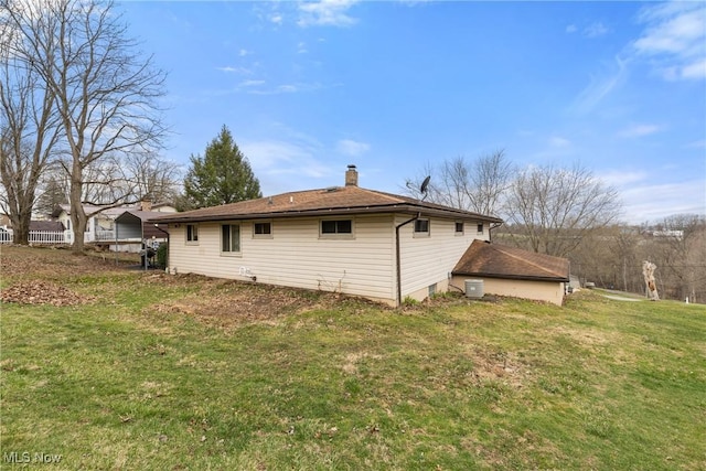 rear view of property with a chimney and a yard