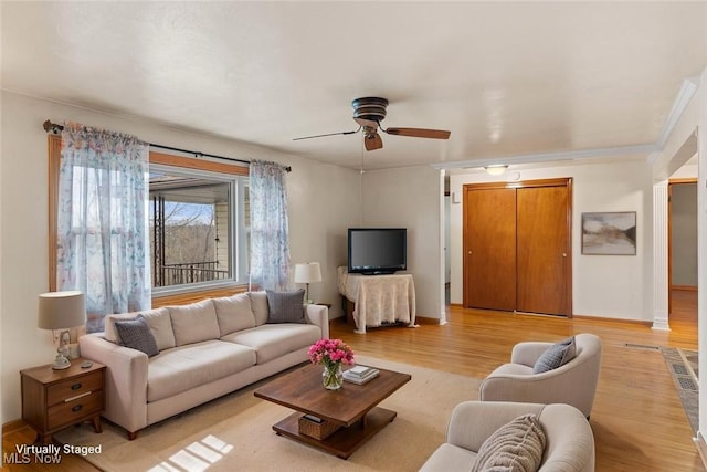 living area featuring ceiling fan, light wood-style flooring, and baseboards