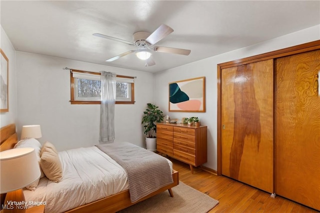 bedroom with ceiling fan, light wood finished floors, and a closet