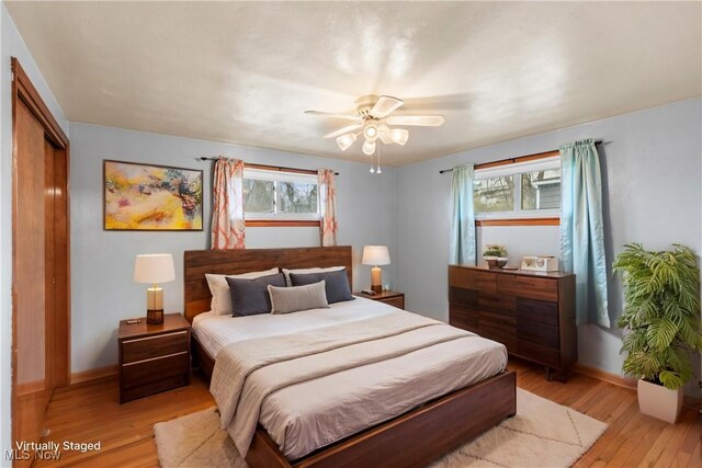 bedroom featuring multiple windows, a closet, light wood-style flooring, and baseboards