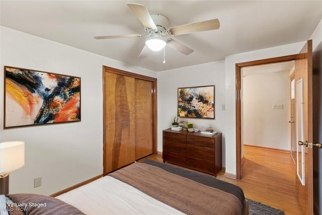 bedroom featuring a closet, a ceiling fan, light wood-style floors, and baseboards