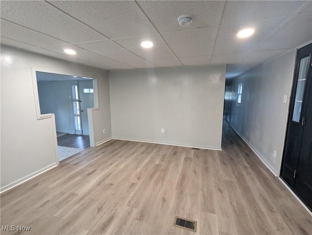 spare room featuring visible vents, light wood-style flooring, baseboards, recessed lighting, and a paneled ceiling
