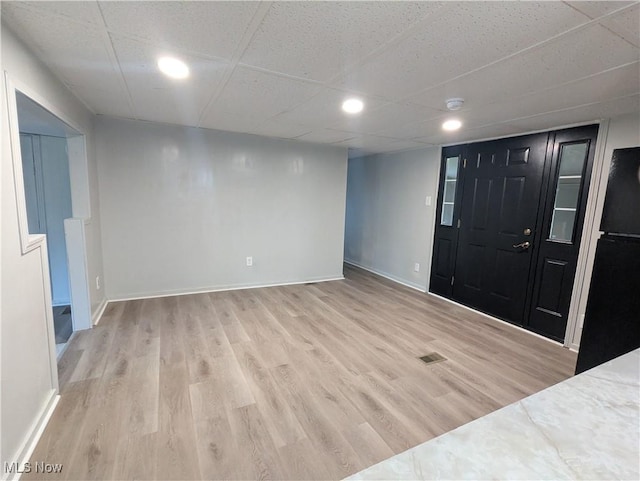 foyer featuring light wood finished floors, baseboards, visible vents, recessed lighting, and a paneled ceiling