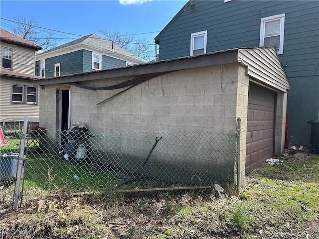 view of home's exterior featuring fence, an attached garage, and concrete block siding