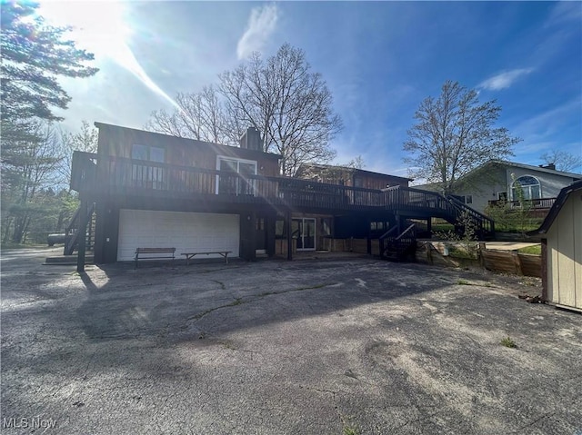 3013 Whispering Pines Dr, Canfield, OH 44406 - rear view of property featuring driveway, a chimney, a wooden deck, a garage, and stairs