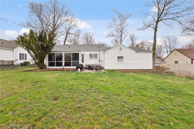rear view of house featuring a sunroom, fence, and a yard