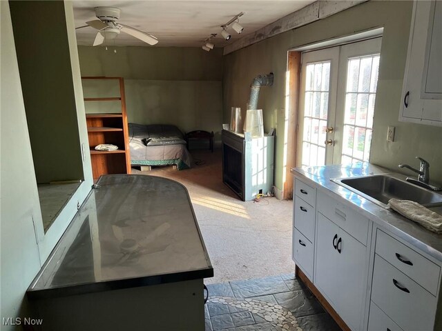 6232 Weaver Rd, Conneaut, OH 44030 - kitchen with french doors, a sink, white cabinets, a ceiling fan, and light carpet
