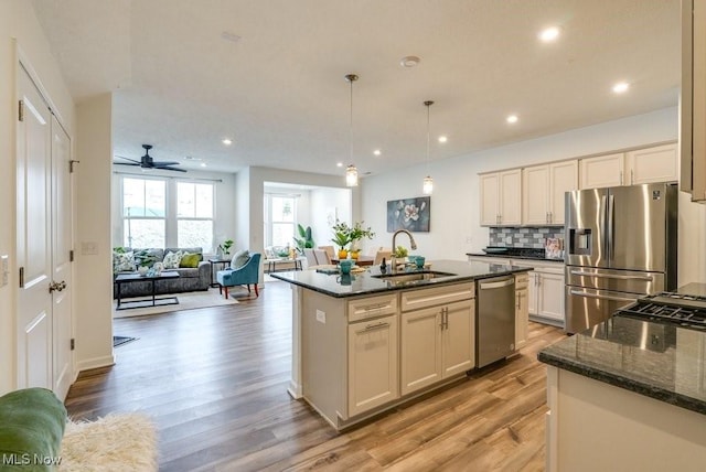 855-2 Dipper Ln, Aurora, OH 44202 - kitchen with stainless steel appliances, light wood-style flooring, dark stone countertops, open floor plan, and tasteful backsplash