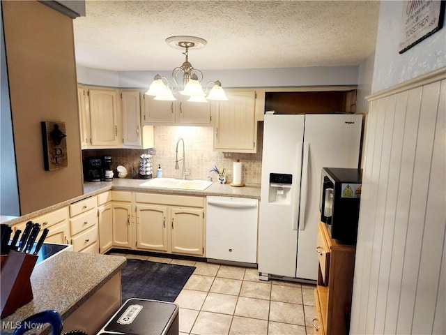 kitchen with a sink, a chandelier, white appliances, backsplash, and light countertops