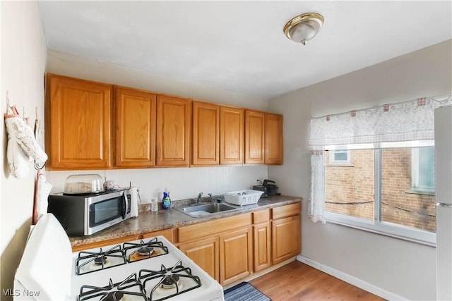 17809 Harvard Ave, Cleveland, OH 44128 - kitchen with baseboards, stainless steel microwave, white range with gas cooktop, a sink, and light wood-style floors