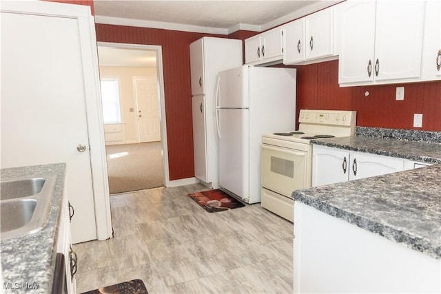 kitchen featuring white appliances, ornamental molding, a sink, dark countertops, and white cabinets