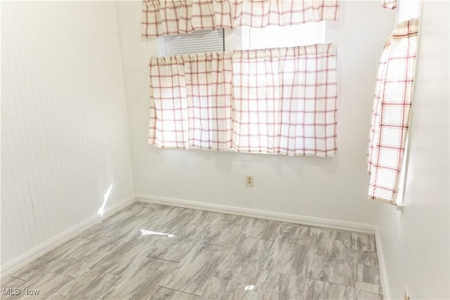 unfurnished room featuring wood tiled floor and baseboards