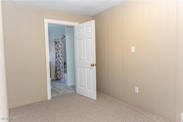 unfurnished room with wood walls and carpet flooring