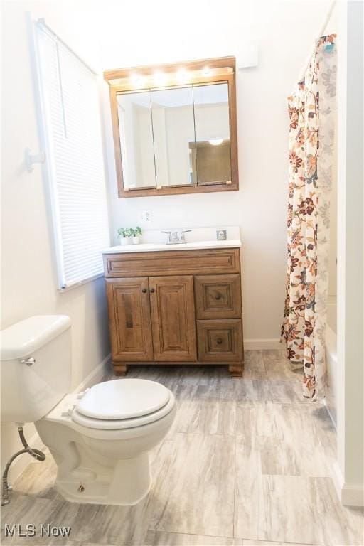 full bath with baseboards, shower / bath combination with curtain, toilet, and vanity