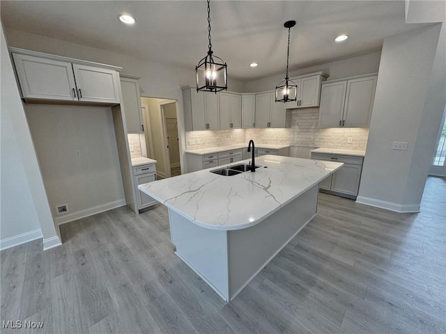 32062 Tuscan Ln Unit L-4, Avon Lake, OH 44012 - kitchen featuring a sink, tasteful backsplash, an island with sink, and light wood-type flooring