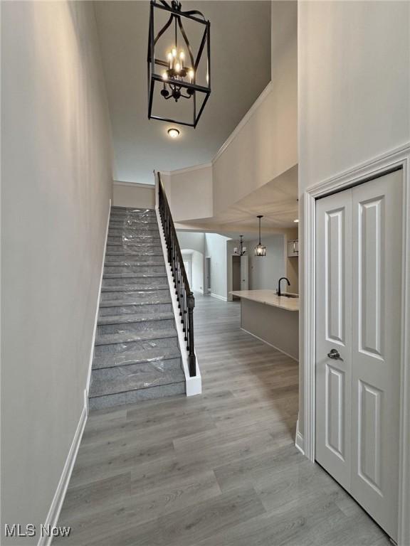 32062 Tuscan Ln Unit L-4, Avon Lake, OH 44012 - stairs featuring an inviting chandelier, ornamental molding, baseboards, and wood finished floors
