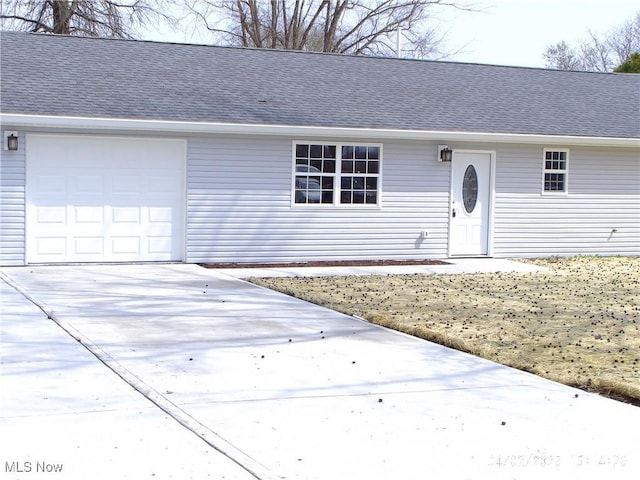 ranch-style house with concrete driveway, roof with shingles, and an attached garage