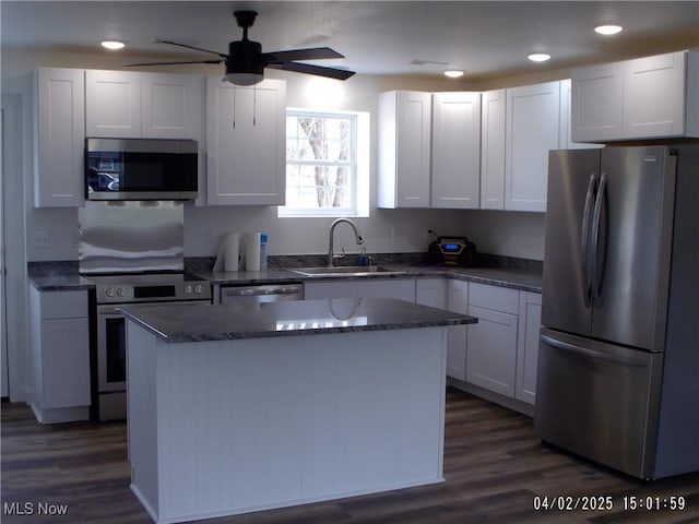 kitchen with dark wood-style flooring, a sink, a center island, and appliances with stainless steel finishes