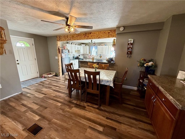 dining space with dark wood-style floors, a textured ceiling, and ceiling fan