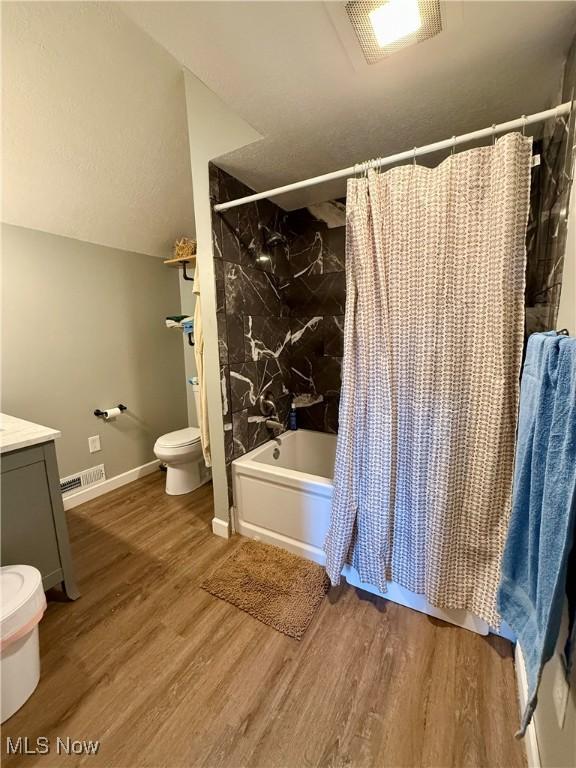 full bathroom featuring vanity, toilet, visible vents, shower / bath combo, and wood finished floors