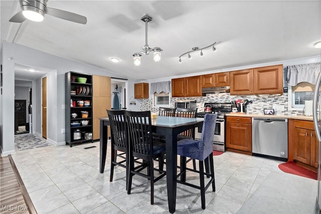 dining room featuring ceiling fan with notable chandelier, lofted ceiling, and baseboards