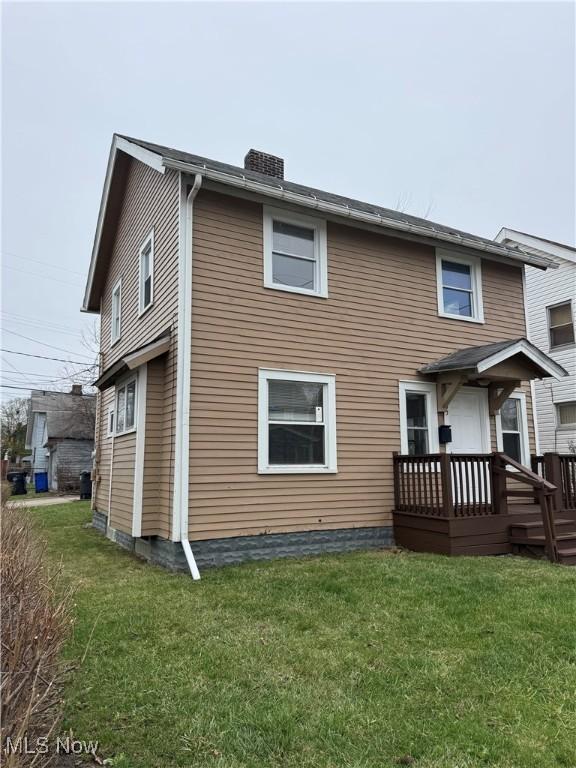 rear view of house with a chimney and a yard