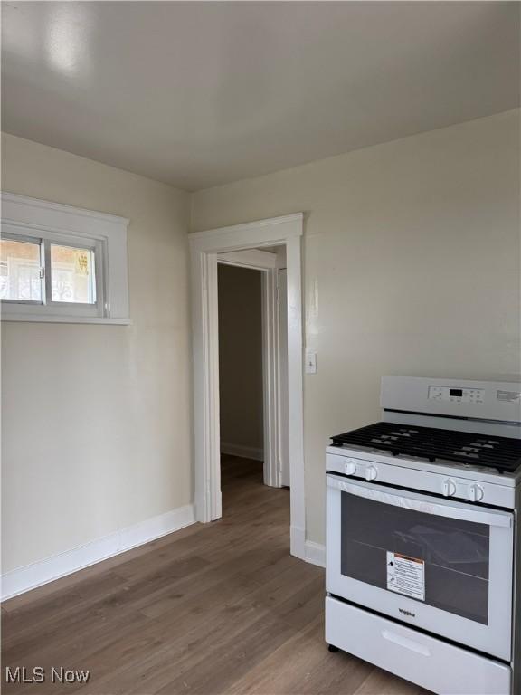 kitchen with white range with gas cooktop, baseboards, and wood finished floors