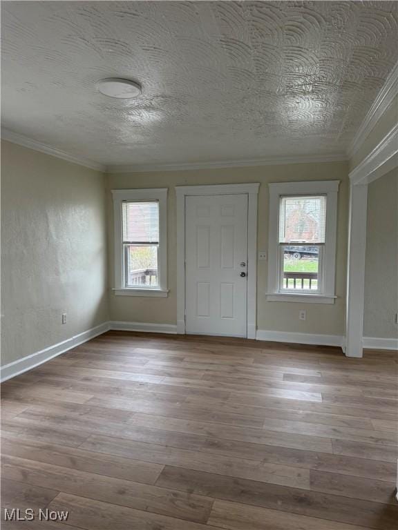 foyer entrance with a wealth of natural light, wood finished floors, ornamental molding, and a textured ceiling