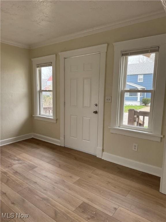 entrance foyer featuring light wood-style flooring, ornamental molding, and baseboards