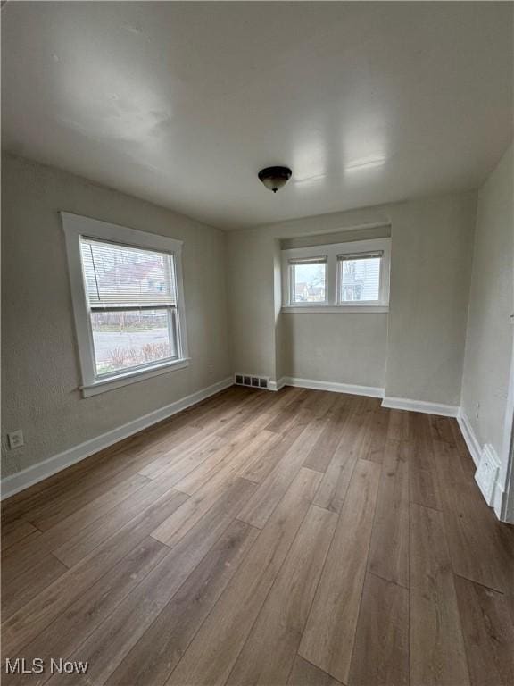 unfurnished room with baseboards, visible vents, and wood finished floors