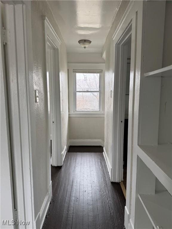 corridor with dark wood-type flooring and baseboards