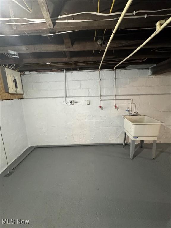 unfinished basement featuring a sink and electric panel