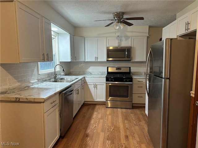 kitchen with white cabinetry, light countertops, stainless steel appliances, a sink, and light wood-style floors