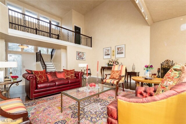 living room with wood finished floors, track lighting, baseboards, a high ceiling, and stairs