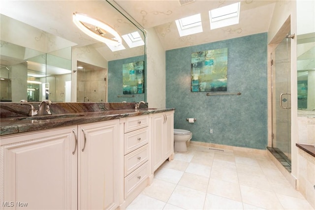bathroom with a sink, double vanity, toilet, a shower stall, and lofted ceiling with skylight