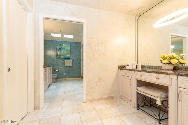 bathroom with vanity, tile patterned flooring, baseboards, and toilet