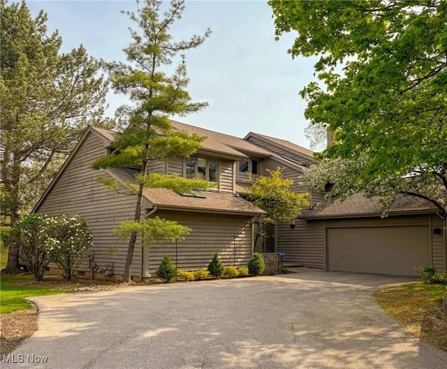 view of front facade with a shingled roof and driveway