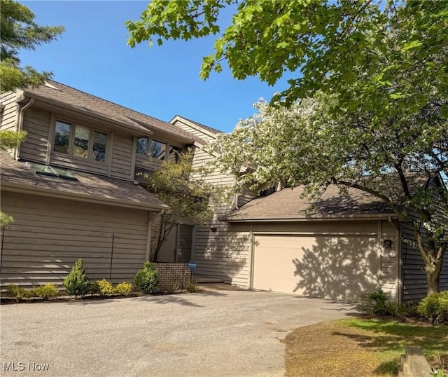 view of front of property with a shingled roof and concrete driveway