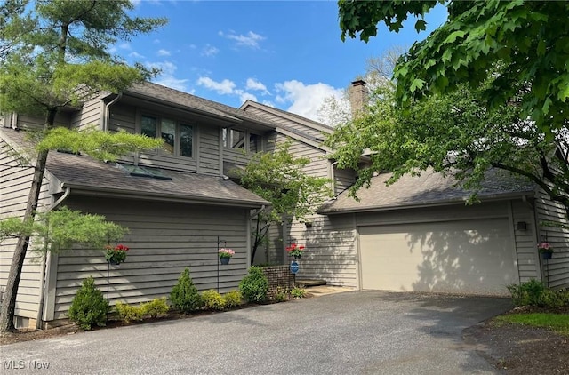 2 Salem Ct, Beachwood, OH 44122 - view of property exterior featuring roof with shingles, aphalt driveway, and a chimney