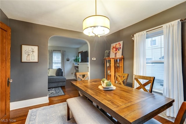 dining room with baseboards, wood finished floors, and arched walkways